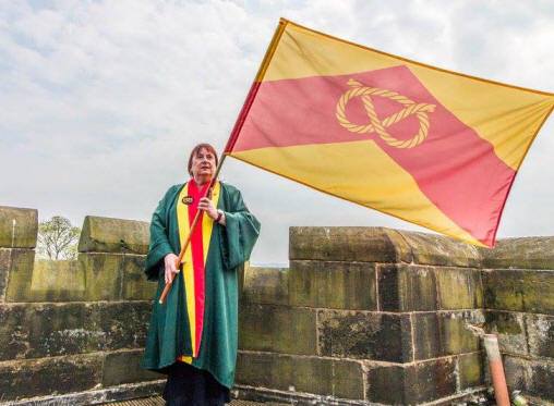 Carol Lake of the Stafford Burgesses Guild with the Staffordshire county flag on the roof of Caverswall Castle